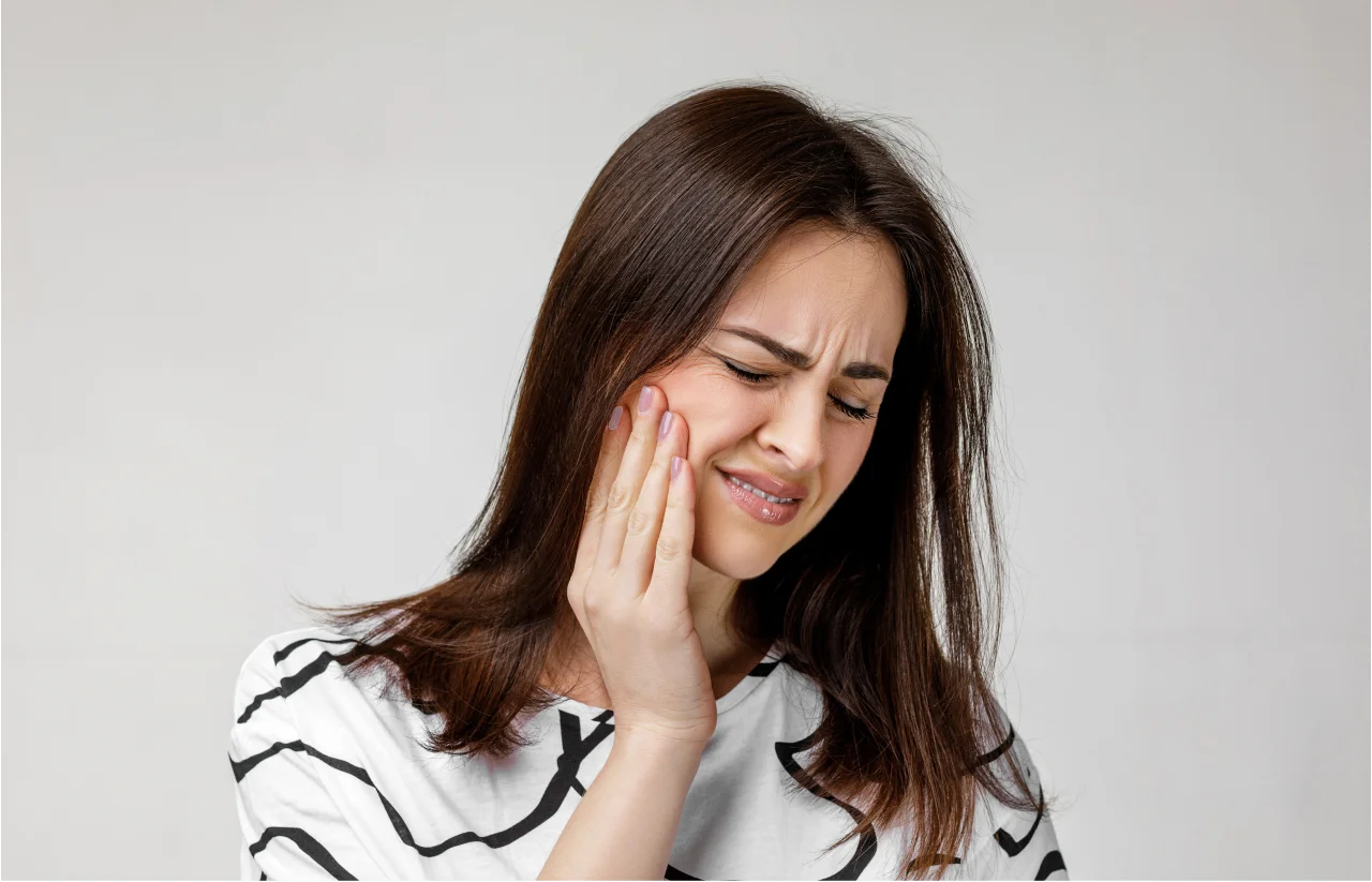 Woman with concerned expression touching her face showing signs of dental discomfort