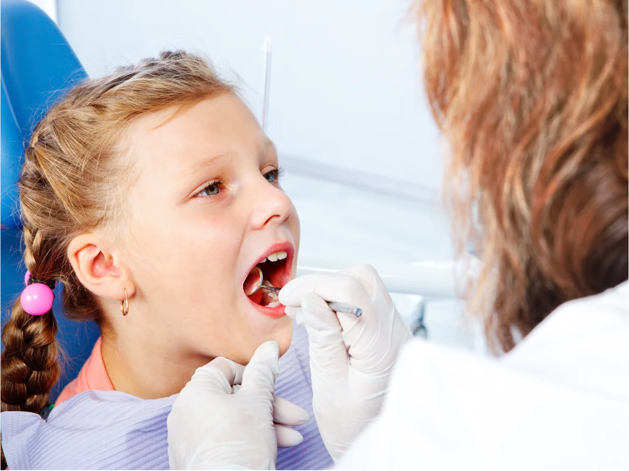 Dentist examining young child's open mouth during pediatric dental checkup