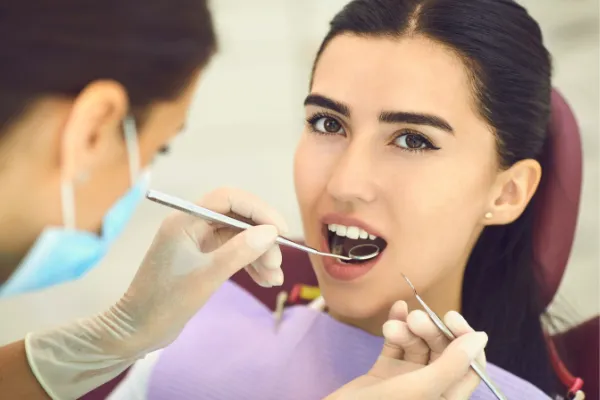 Dental hygienist performing professional teeth cleaning examination on female patient