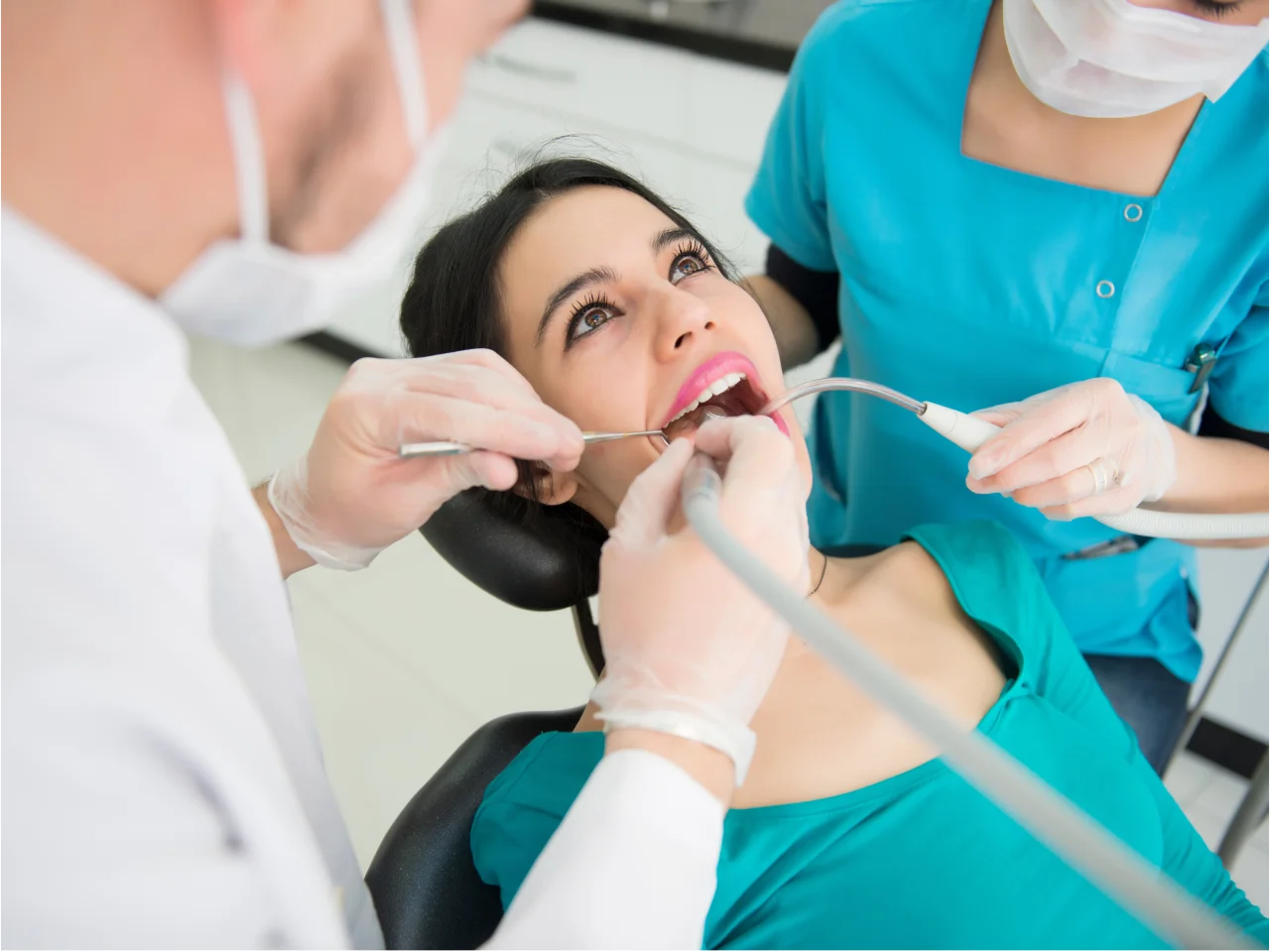 Dental hygienist performing professional teeth cleaning on patient in dental chair"