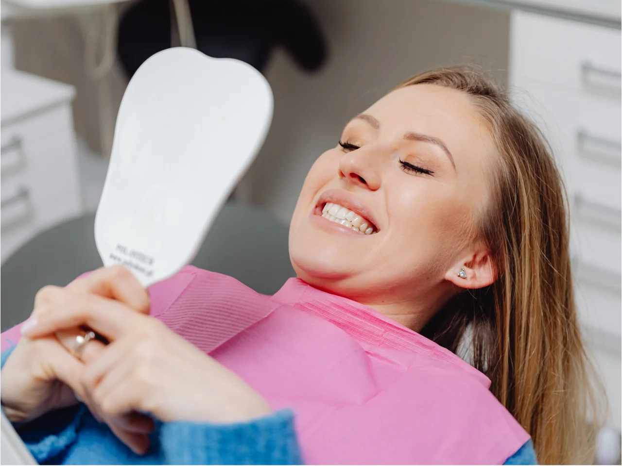 Smiling woman in dental chair showing her bright white teeth after cosmetic dental treatment