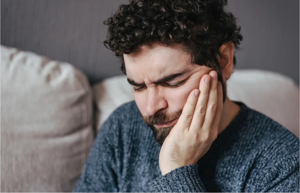 Man holding both hands to face showing signs of severe dental pain and distress