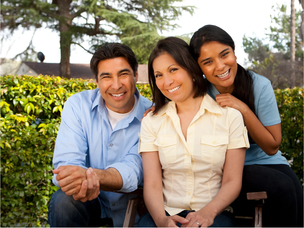 Happy family of three generations including senior man, middle-aged woman, and young woman smiling together outdoors