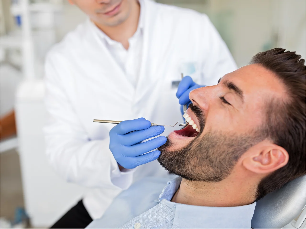 Dentist performing oral examination on male patient during preventative dental checkup