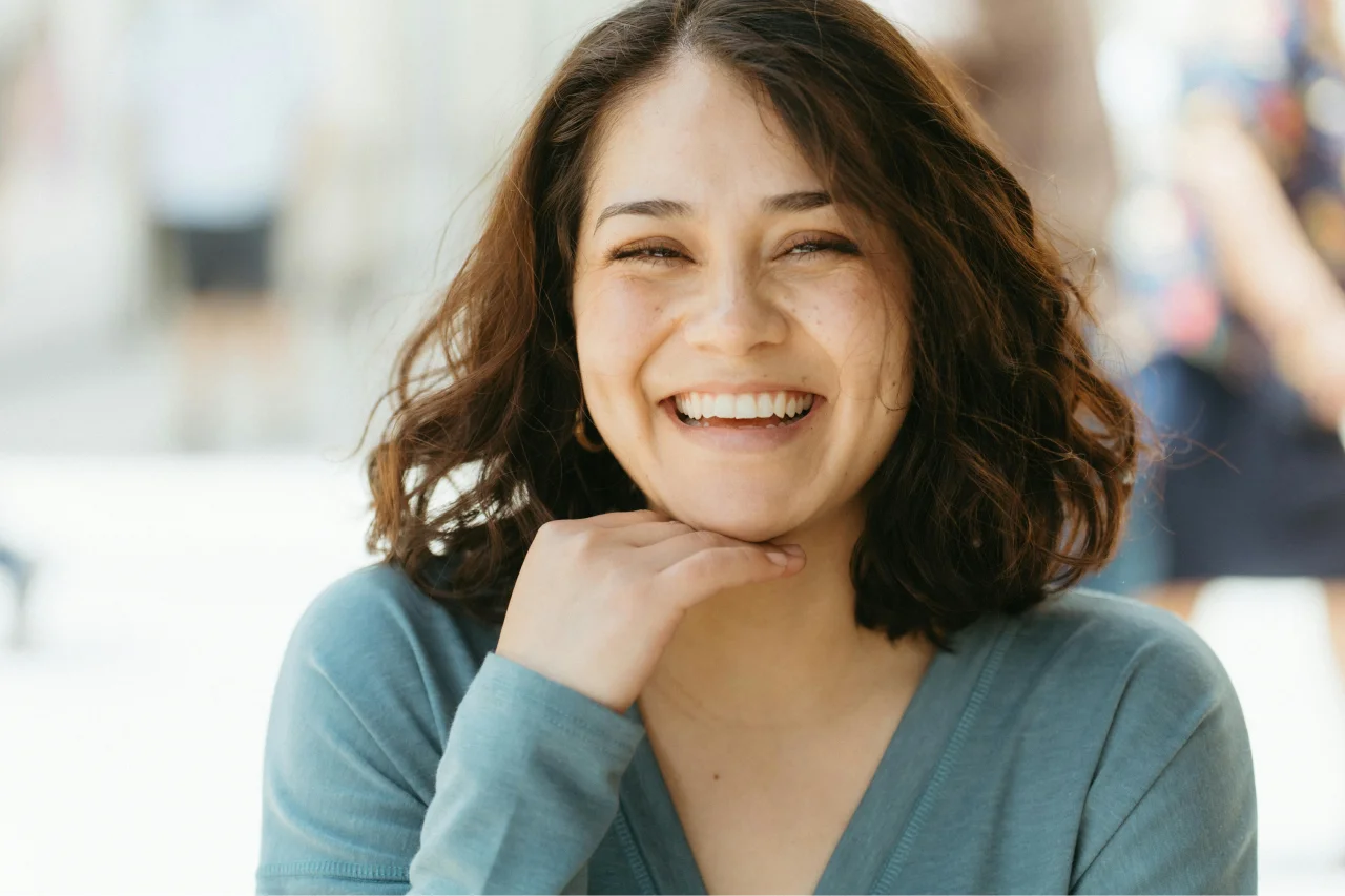 Smiling woman with short brown hair resting chin on hand showing confident happy smile