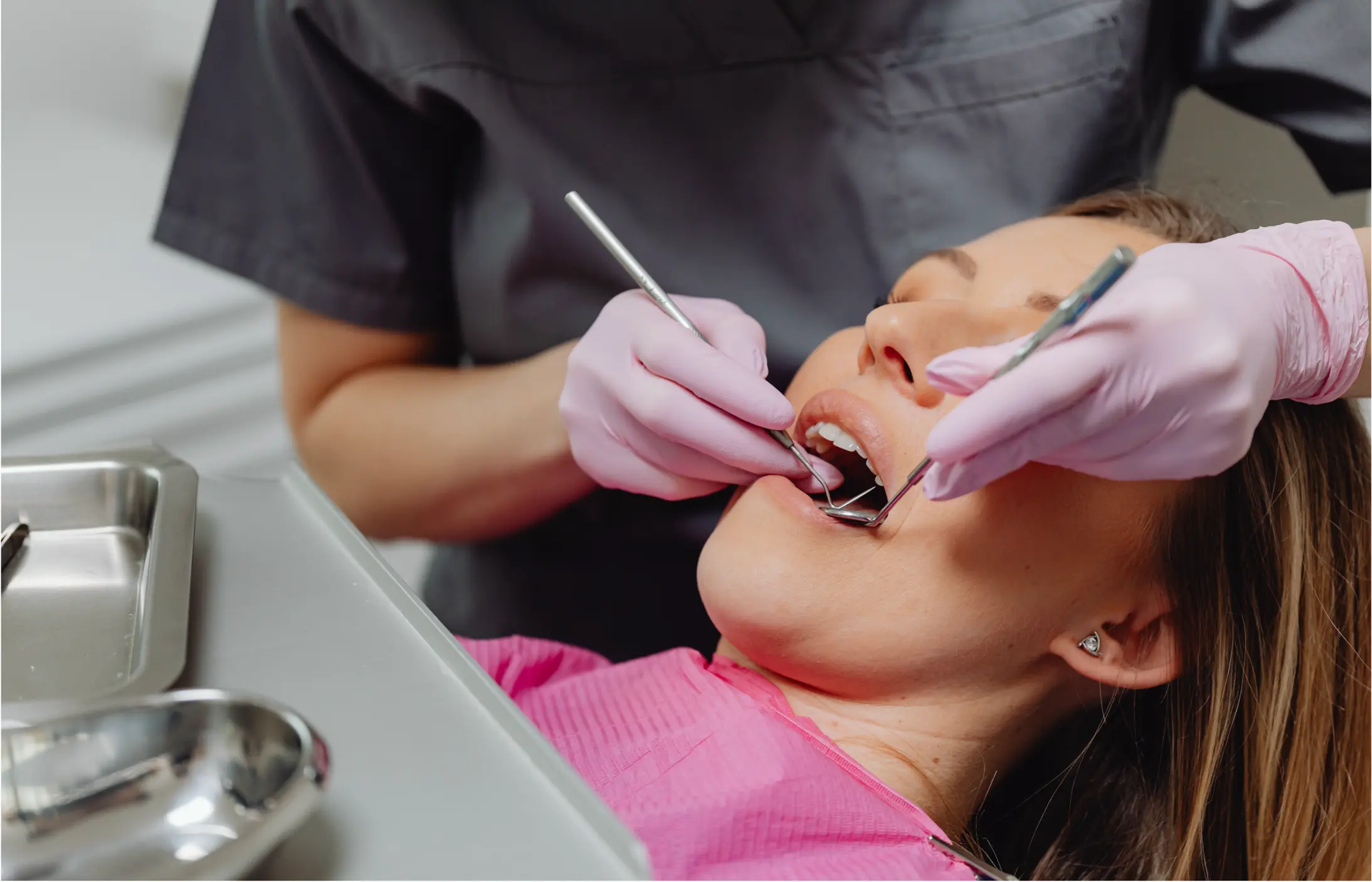Patient in dental chair receiving professional teeth cleaning with dentist using dental instruments