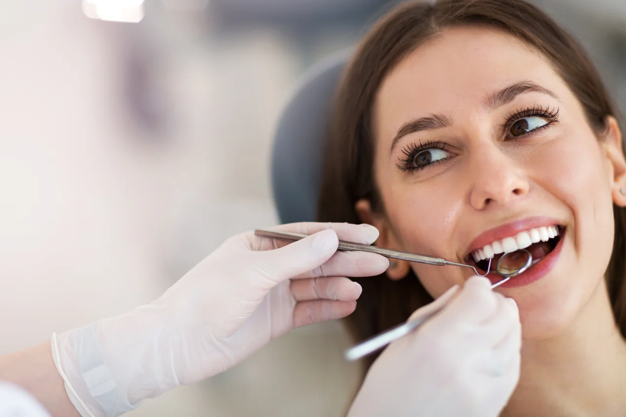 Woman looking in mirror examining her bright white teeth and smile