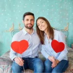 Happy couple holding red hearts celebrating Valentine's Day dental promotion at Davis Dental Group in Tacoma