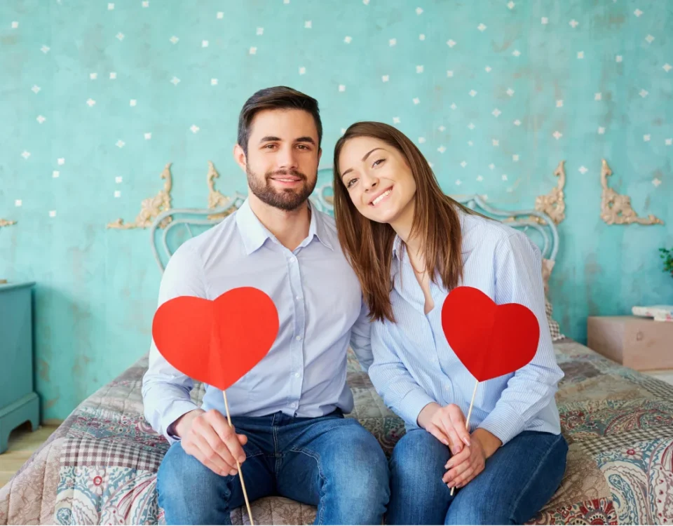Happy couple holding red hearts celebrating Valentine's Day dental promotion at Davis Dental Group in Tacoma
