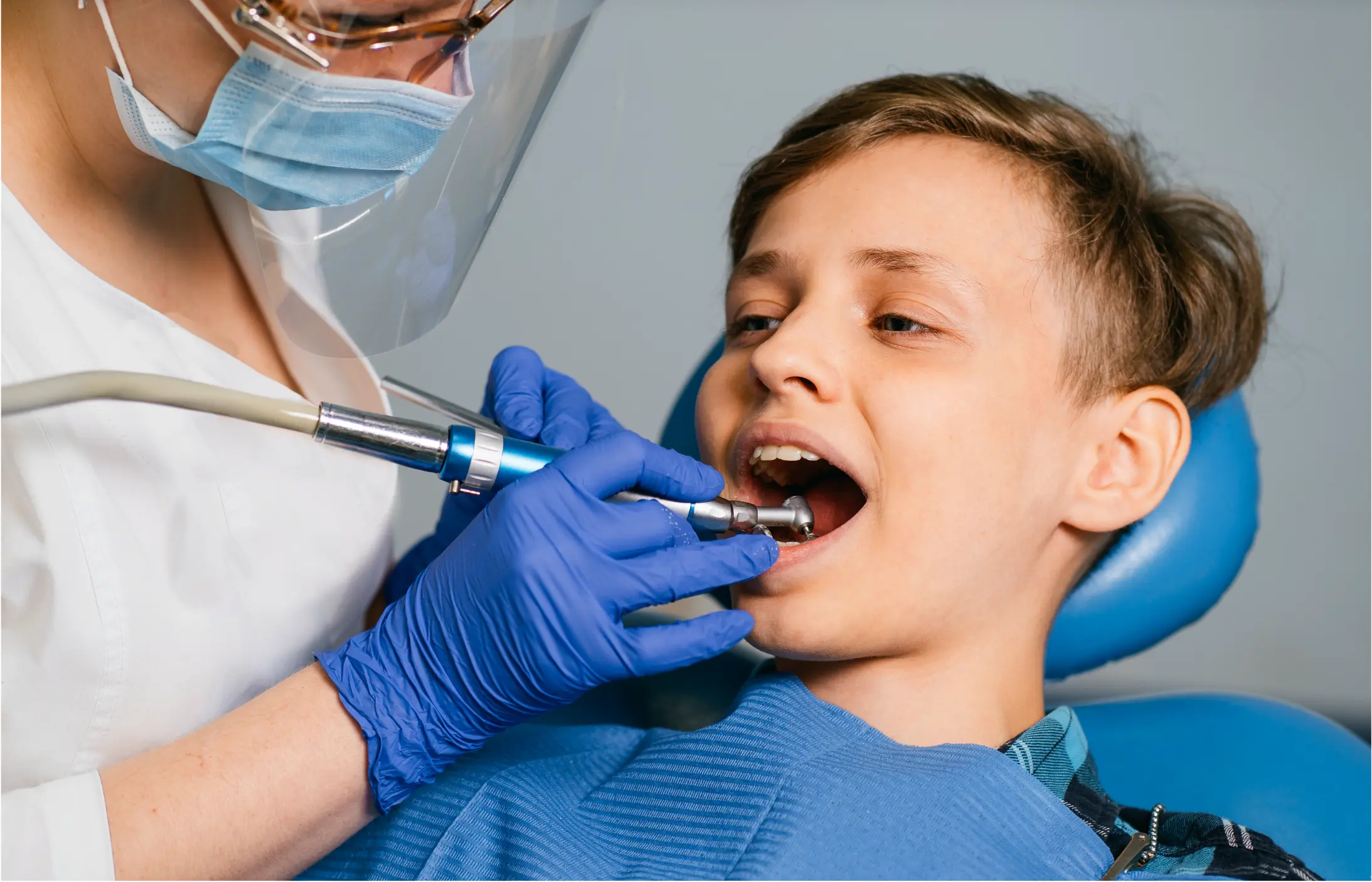 Child in dental chair receiving dental examination from pediatric dentist