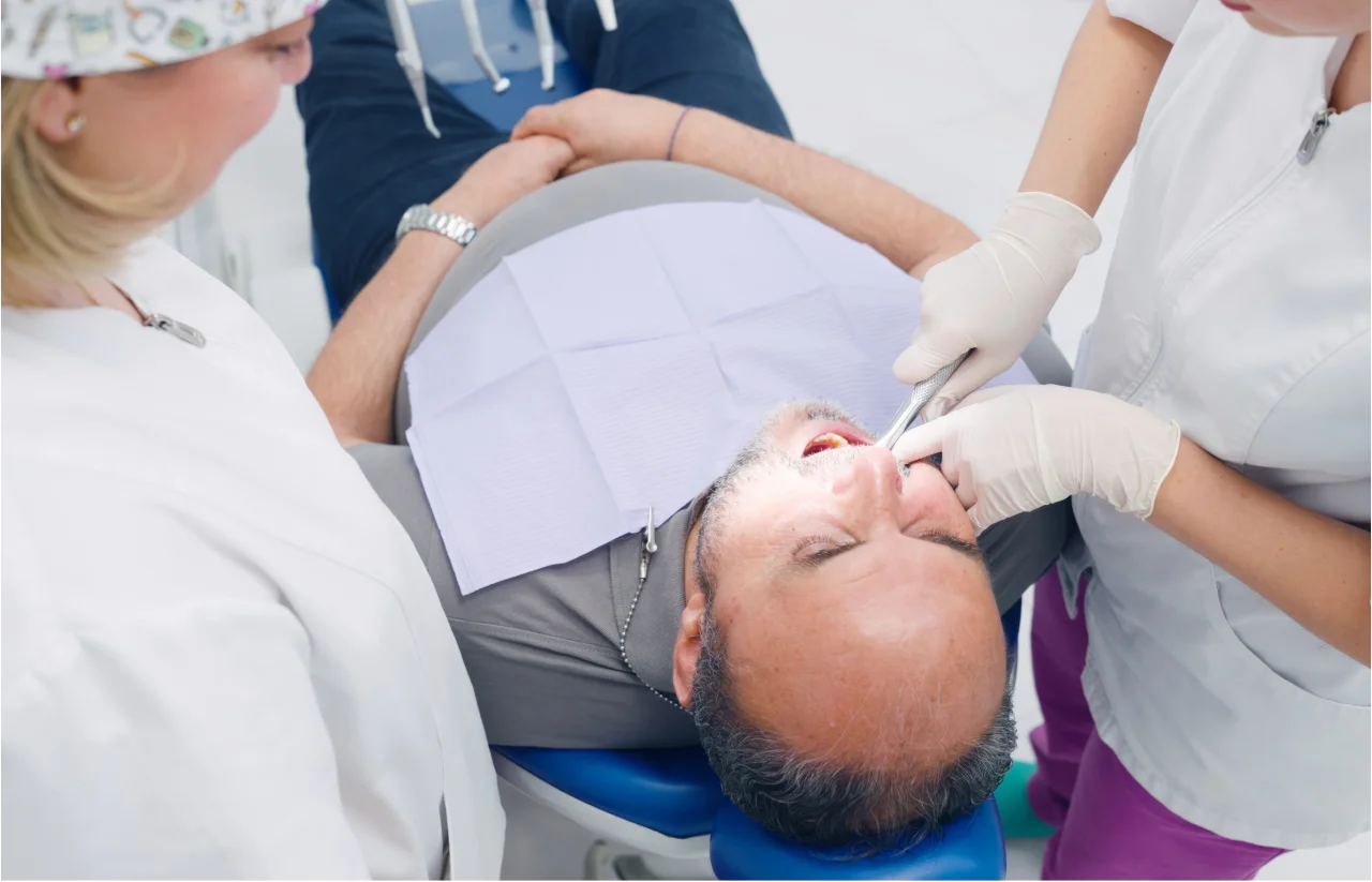 Patient in dental chair receiving tooth extraction procedure from dentist