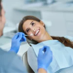 A smiling patient in a dental chair during a checkup for National Dentist's Day.