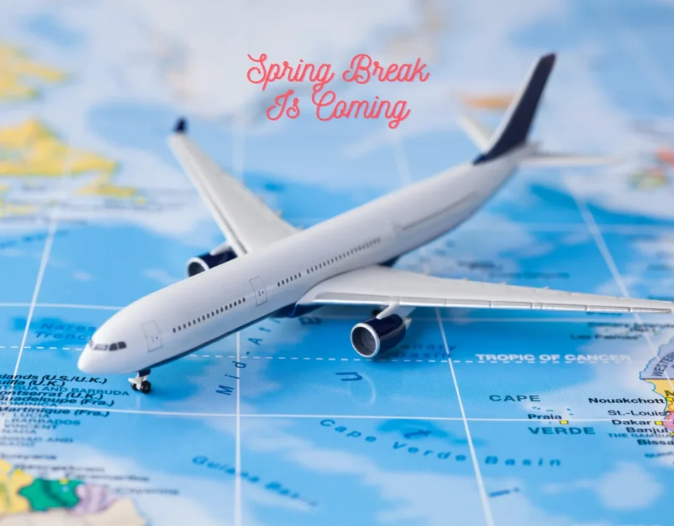 A toy airplane resting on a world map with "Spring Break Is Coming" text, representing travel plans for Tacoma and JBLM families.
