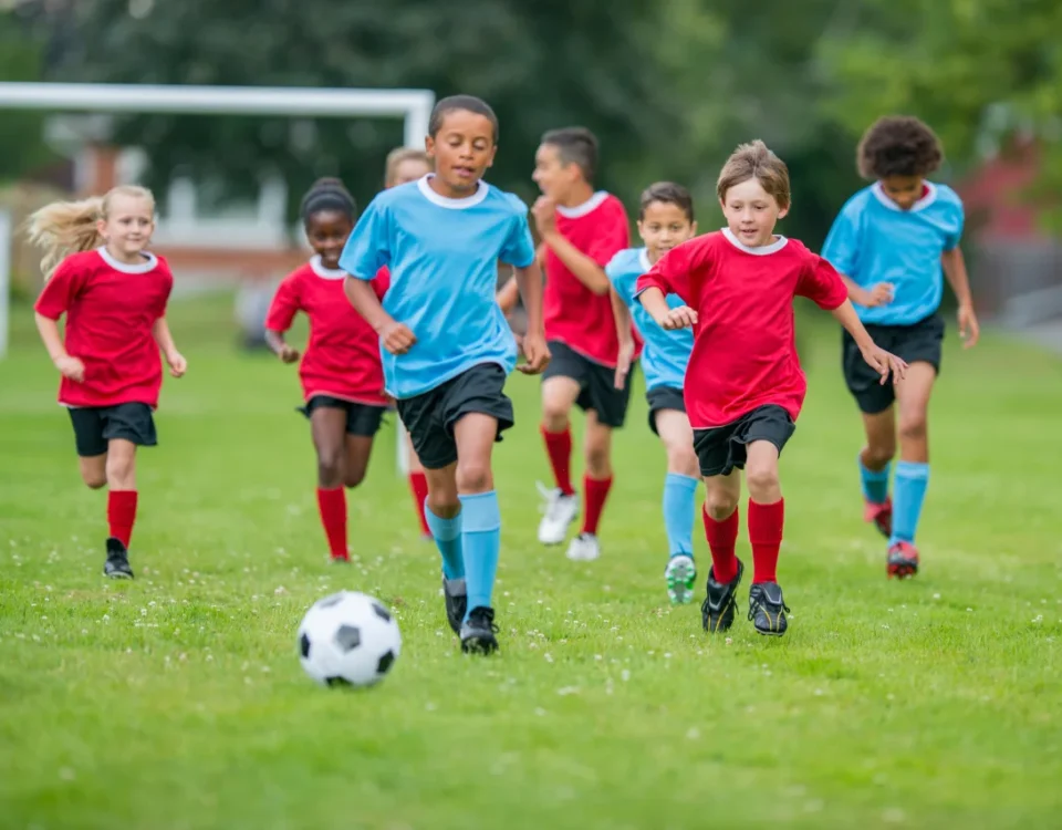 Children playing soccer on grassy field