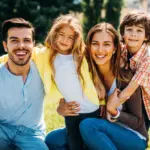 Happy family smiling outdoors in summer representing family dentist in Tacoma services at Davis Dental Group