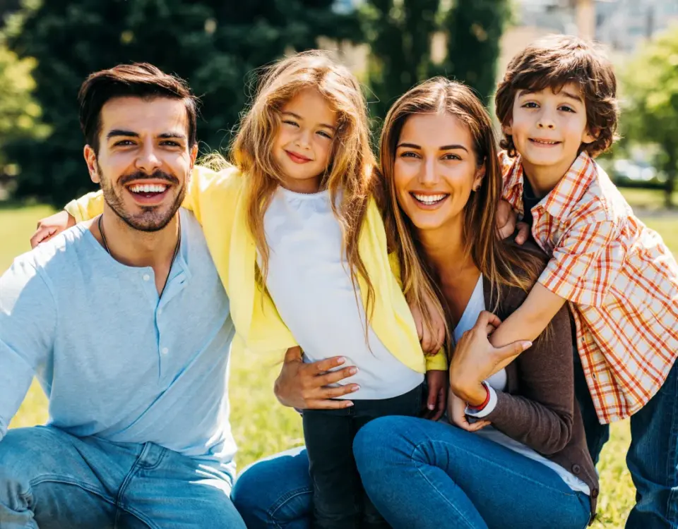 Happy family smiling outdoors in summer representing family dentist in Tacoma services at Davis Dental Group