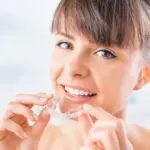 Woman inserting clear aligners tacoma wa at Davis Dental Group showing how transparent aligner trays fit over teeth