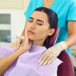 Patient holding jaw in pain at Davis Dental Group in Tacoma discussing tooth extractions and damaged tooth treatment options